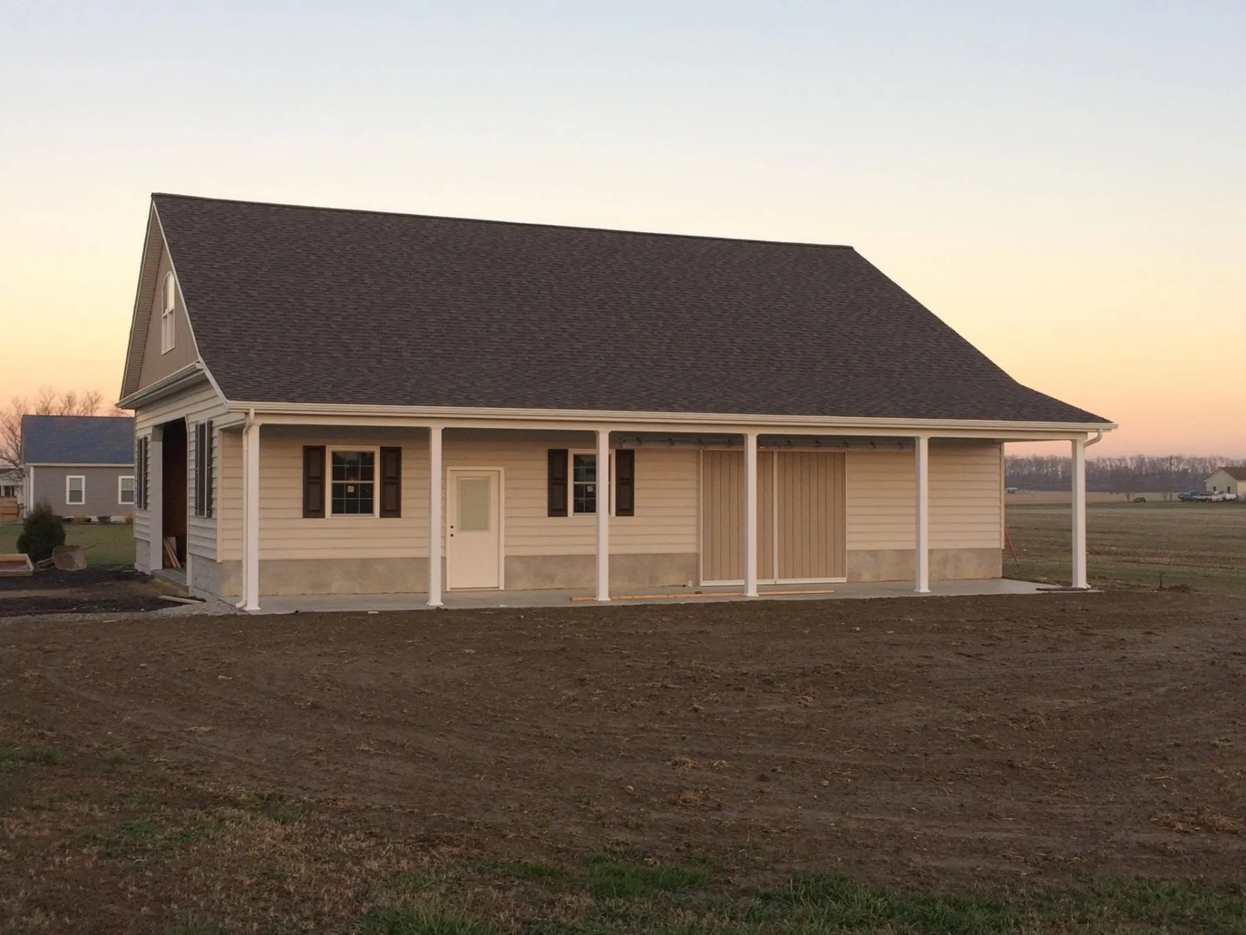 Completed home with a covered front porch at dusk